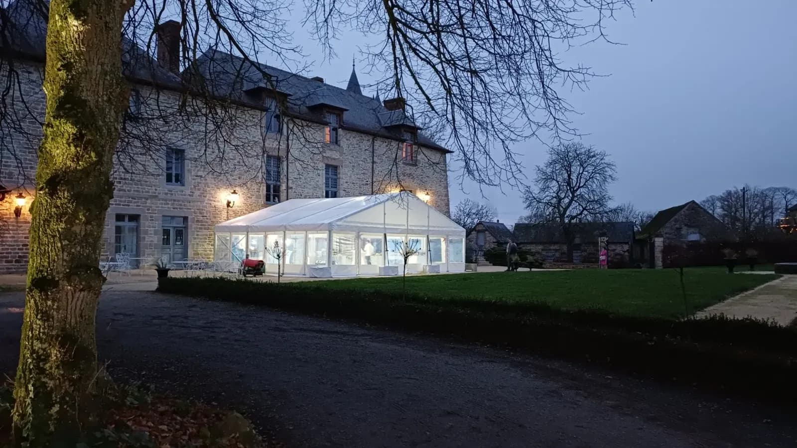 Chapiteau éclairé devant un château à la tombée de la nuit