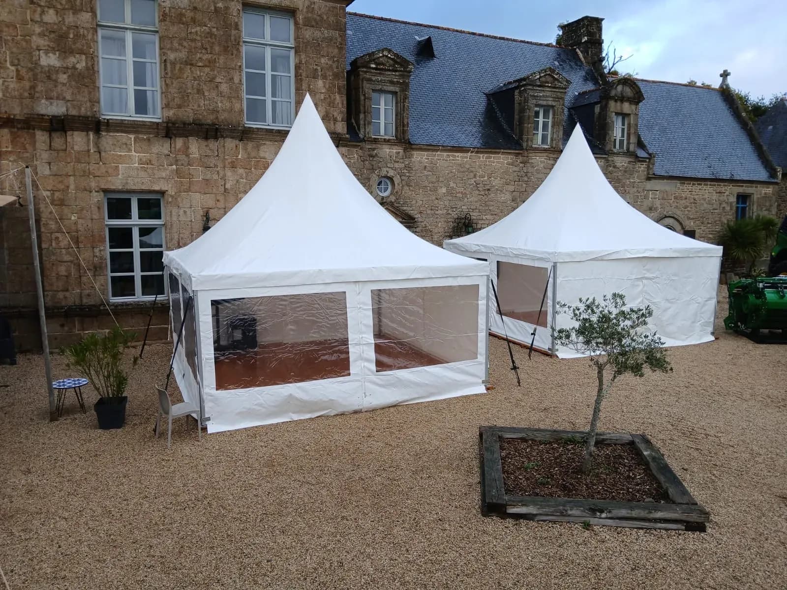 Deux tentes pagodes dans la cour gravillonnée d'un domaine en pierre