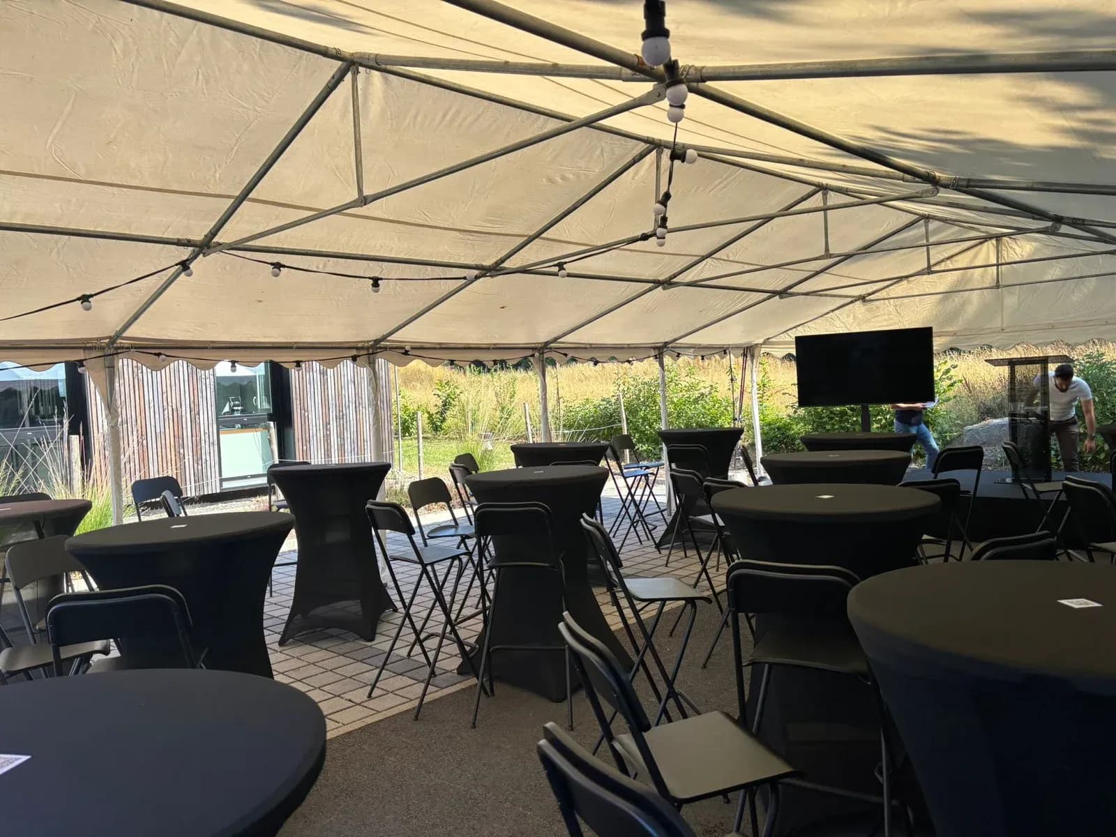 Tables hautes et mange-debout sous un chapiteau, pour un cocktail