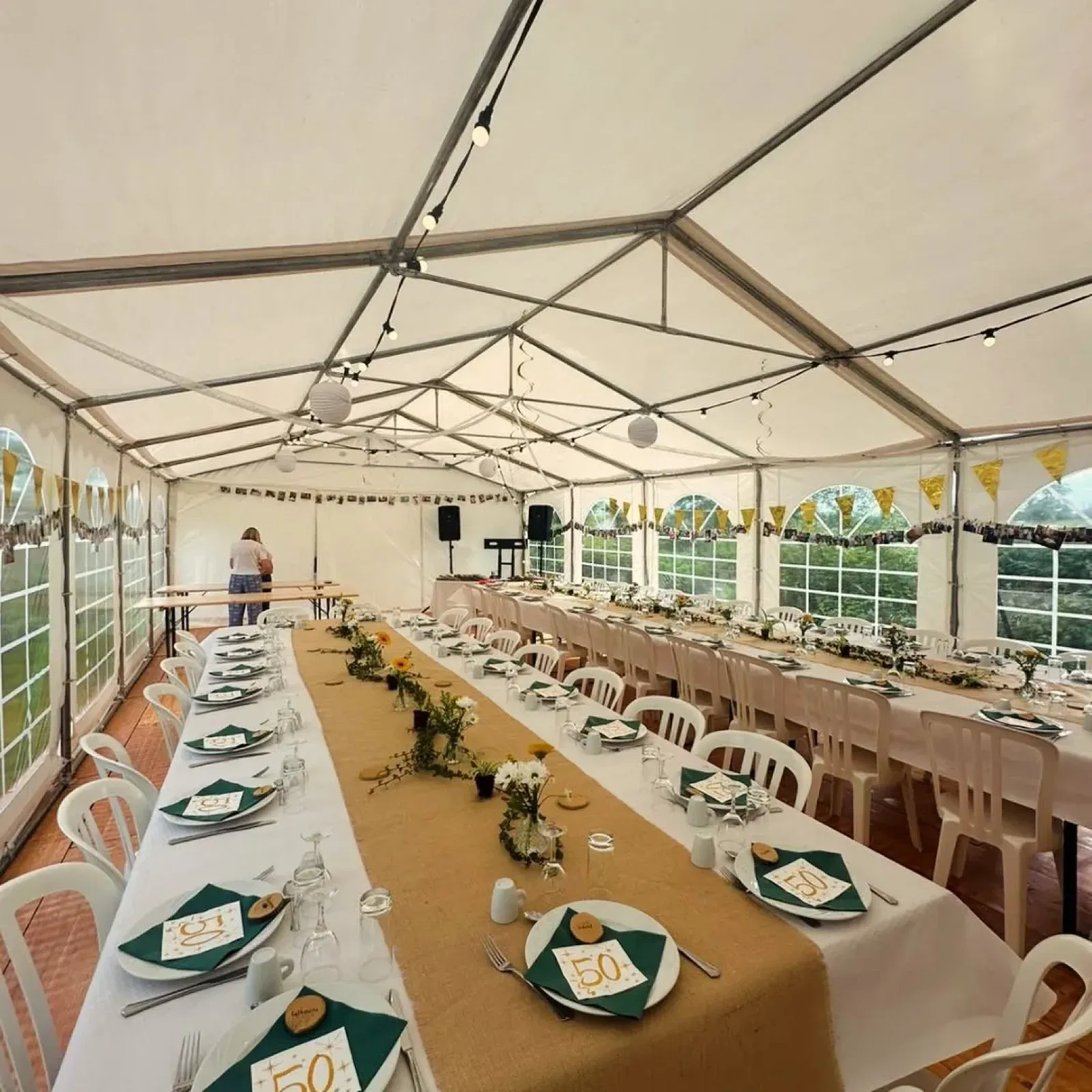 Tables de banquet alignées sous un chapiteau, fanions et guirlandes