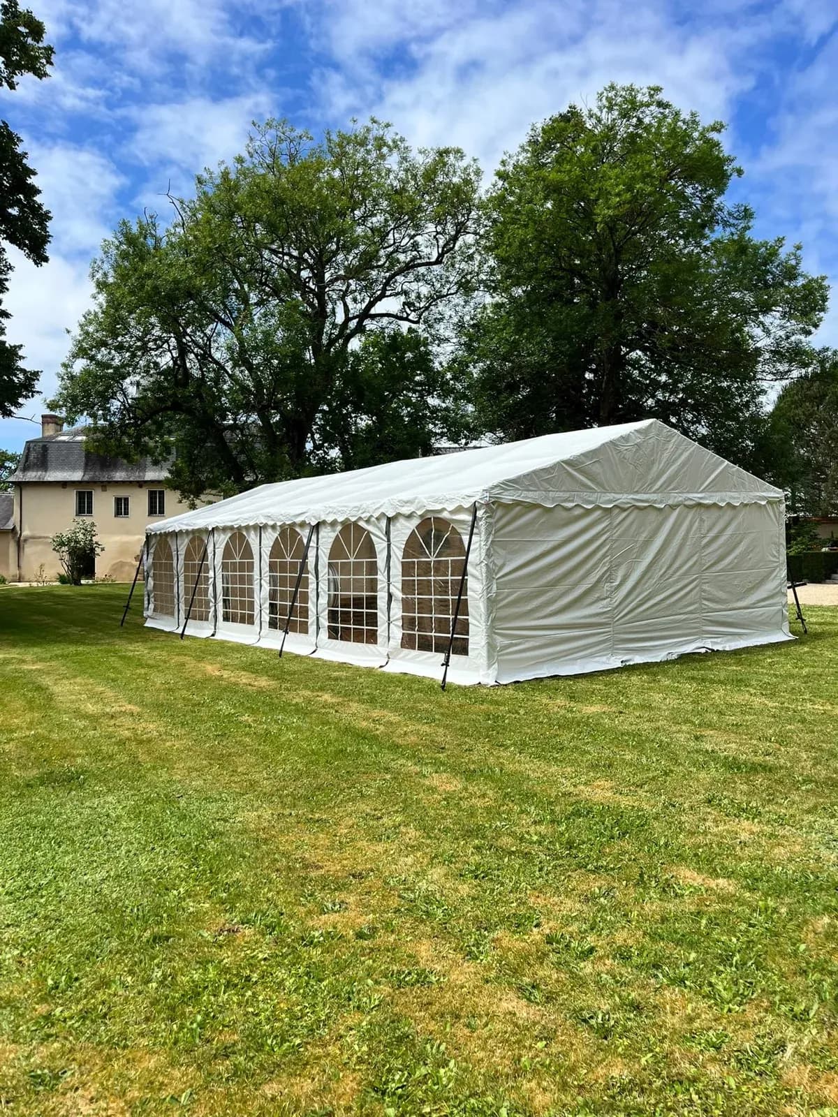Chapiteau blanc dressé dans le parc d'une demeure en pierre